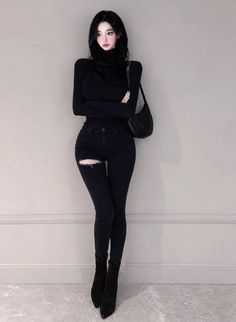 Woman in a black turtleneck and ripped jeans with a black handbag