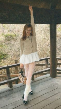 Woman in a white skirt and cardigan with a leopard print bag outdoors
