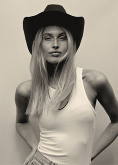 Woman in a cowboy hat and white tank top with long blonde hair