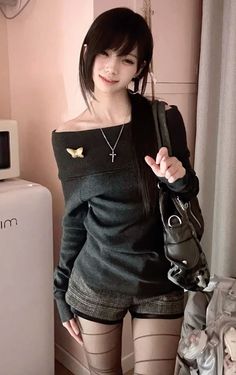Woman with black hair wearing an off-shoulder top and plaid shorts indoors