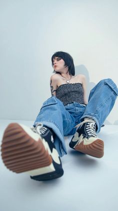 Person with dark makeup and short hair wearing a tube top and baggy jeans