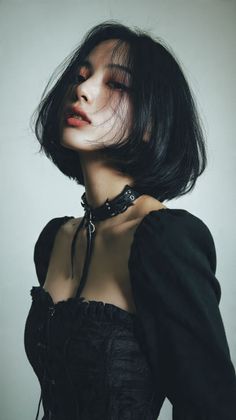 Woman with short black hair wearing a choker and black top