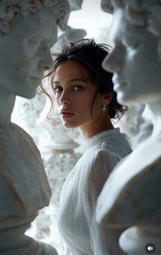 Woman in a white dress surrounded by white sculptures, looking over her shoulder