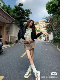 Woman in a pleated skirt and crop top posing on a street