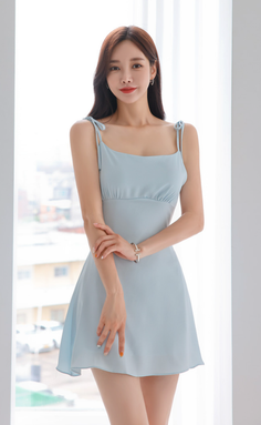 Woman in a light blue dress standing indoors with soft lighting
