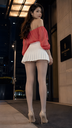 Woman in an off-shoulder top and pleated skirt with pantyhose and high heels at night