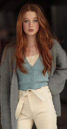 Young woman with long red hair and blue eyes wearing a blue cardigan
