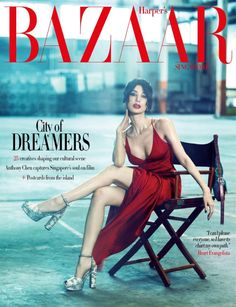 Woman in a red dress and high heels sitting on a chair for a magazine cover