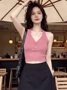 Woman in a pink halter top and black skirt posing in a cafe