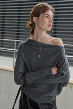 Woman in an off-shoulder gray sweater with a necklace and exposed shoulder