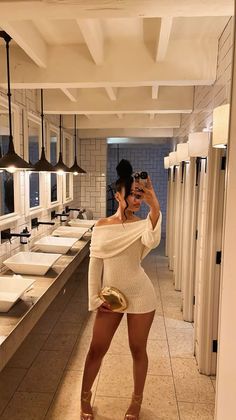 Woman in an off-shoulder dress taking a mirror selfie in a bathroom
