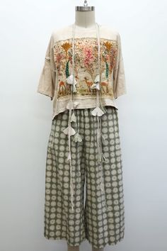 Mannequin wearing an embroidered shirt and floral wide-leg pants with a tassel necklace