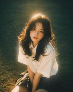 Young woman with long hair in a white shirt and dark skirt, backlit by golden hour sun