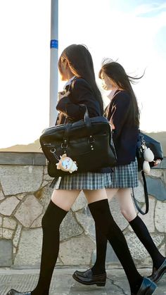 Two students in school uniforms walking outdoors with backlight