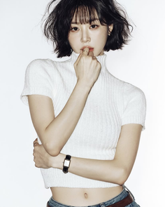 Woman with short black hair wearing a white crop top and jeans