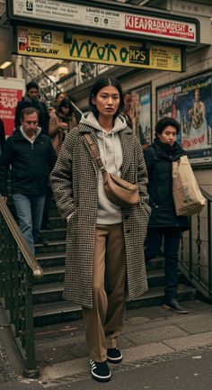 Woman in a houndstooth coat and hoodie in a subway station