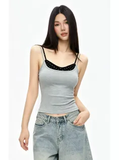 Woman with long dark hair wearing a gray tank top and loose jeans