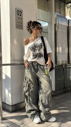 Woman in cargo pants and an off-shoulder top standing outdoors