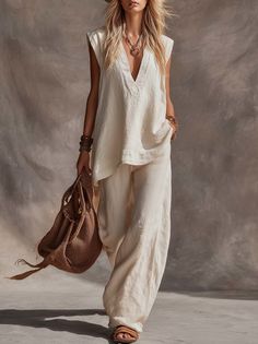 Woman in a cream linen outfit and straw hat holding a straw bag