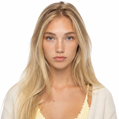 Young woman with blonde hair and freckles wearing a yellow top and cardigan