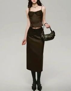 Woman in a dark lace camisole and midi skirt with a shoulder bag