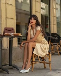 Woman in a polka dot dress sitting at an outdoor cafe table