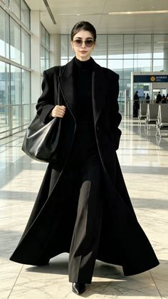 Woman in a black coat and sunglasses walking through an airport