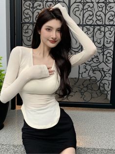 Woman with long dark hair wearing a tight top and black skirt indoors