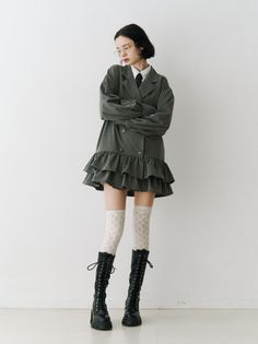 Woman in a pinstripe blazer dress, lace socks, and combat boots against a white background