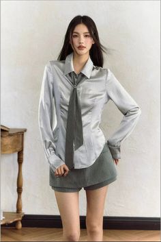 Woman with long dark hair wearing a silver shirt and striped shorts indoors