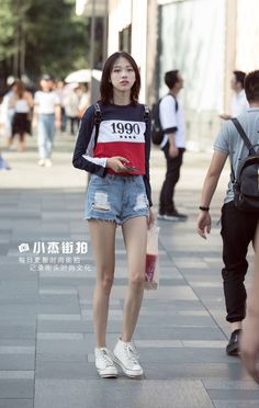 Woman in a striped long-sleeve shirt and ripped denim shorts on a street