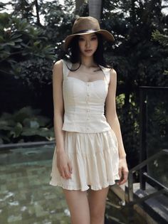 Woman in a straw hat and white outfit standing outdoors