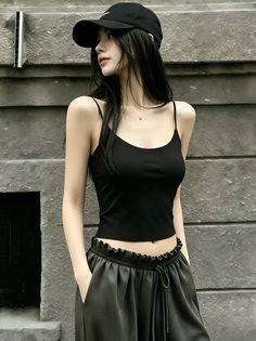 Woman with long black hair wearing a black tank top and baseball cap outdoors