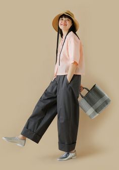 Woman in a straw hat and wide leg pants holding a woven bag