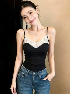 Woman in a black camisole with lace trim and blue jeans, smiling at the camera
