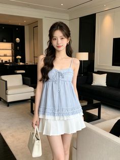 Woman with long hair wearing a blue top and white skirt indoors