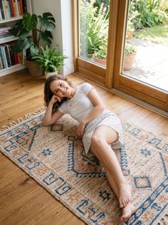 Woman in a white t-shirt and floral skirt lying on a rug indoors