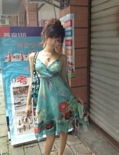 Woman in a blue floral dress standing on a street next to a sign