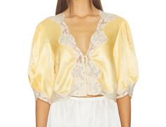Woman wearing a yellow satin and lace cropped top with puffy sleeves
