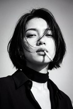 Woman with short hair and a choker, holding a cigarette in her mouth