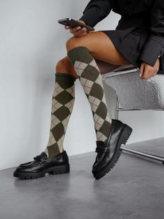 Person wearing argyle socks and black loafers, sitting and holding a phone