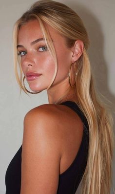 Blonde woman with hoop earrings and freckles looking over her shoulder
