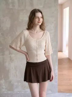 Woman with long wavy hair wearing a knitted top and mini skirt indoors