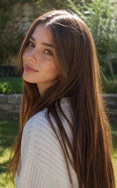 Woman with long brown hair and freckles wearing a white sweater outdoors