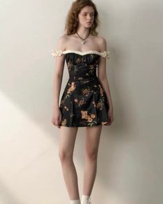 Woman in a black off-shoulder floral dress with a heart necklace