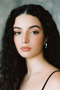 Woman with long dark curly hair and silver hoop earrings