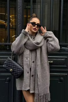 Woman in a gray coat and scarf with sunglasses and an updo