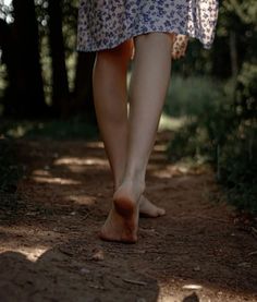 Person walking barefoot on a dirt path in a forest