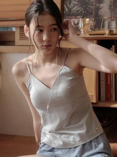Woman in a camisole and earbuds indoors with natural lighting