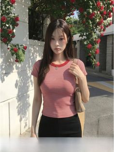 Woman with long hair in a striped shirt standing on a street with red roses